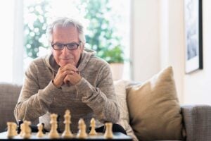 Man weighing the pros and cons of a home equity conversion mortgage over a game of chess