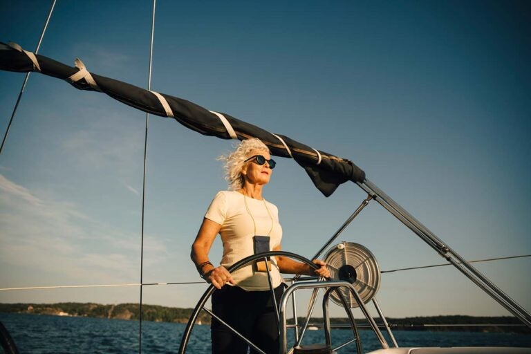 A woman finding meaning in retirement steering a sailboat