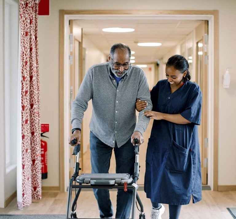 A man being helped by a nurse in an assisted living facility