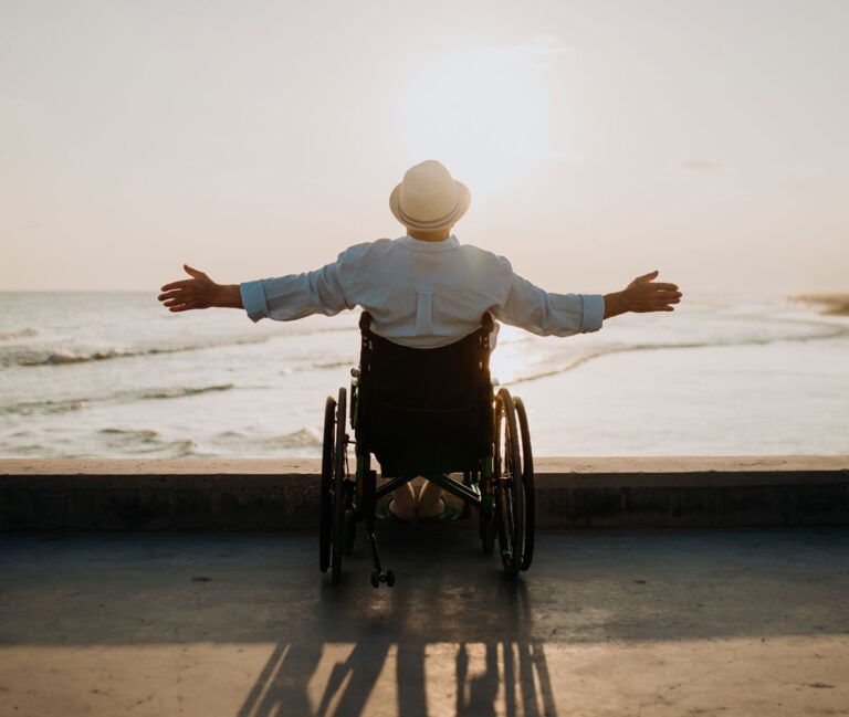 a man enjoying inclusive travel in a wheelchair looks out at a beach