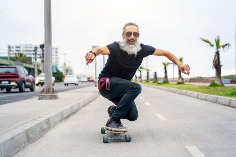 A greyed haired hip guy skateboarding. Definitely not a senior citizen.