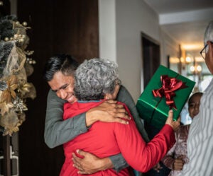 A grandmother and adult grandson rekindle the feeling of home for the holidays with a warm welcome hug.